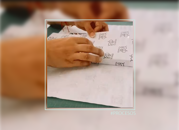 Manos doblando el papel de una libreta durante el proceso de encuadernado en el taller de Ni Paper