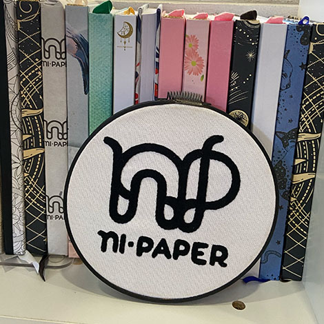 Letrero circular de Ni Paper entre libretas de colores
